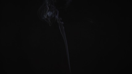 A thin trail of smoke rising across the screen, shot backlit on black background.