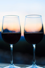 Two glasses of wine at sunset dramatic sky on mountain landscape background