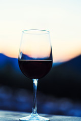 Two glasses of wine at sunset dramatic sky on mountain landscape background