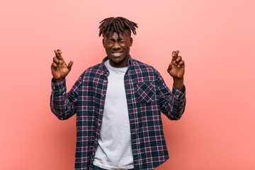 Young african black man crossing fingers for having luck