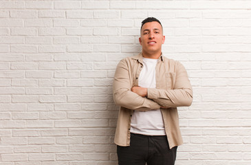 Young latin man crossing arms, smiling and relaxed