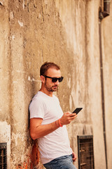 Modern guy using cellphone in the European city.