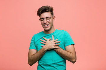 Young cool caucasian man laughing keeping hands on heart, concept of happiness.