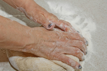 Female hands knead the dough with flour on a white kitchen table. Top view. baking preparation stage, cooking