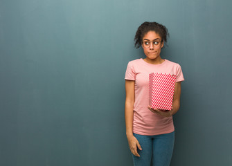 Young black woman thinking about an idea. She is holding a popcorns bucket.