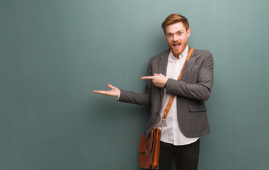 Young redhead business man holding something with hand