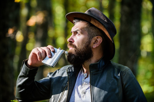 Nomadic Man Carry Alcohol With Him. Guy Brutal Bearded Cowboy Drink Alcohol Metal Flask. Hipster With Beard Drink Alcohol Nature Background Defocused. Adventure Begins From First Sip. Alcohol Drink