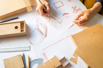 Designer draws a mockup for crafting cardboard box. Development of packaging design sketch. 