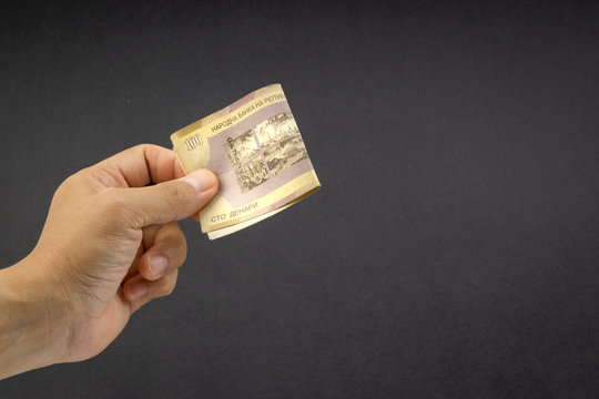 Hand holds one hundred MACEDONIA CURRENCY, Macedonian denar Bank note on black background. Selective focus