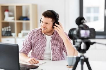 blogging, videoblog and people concept - male blogger with camera recording video review of headphones at home office