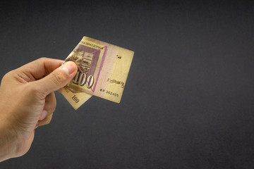 Hand holds one hundred MACEDONIA CURRENCY, Macedonian denar Bank note on black background. Selective focus