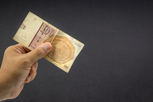 Hand holds one hundred MACEDONIA CURRENCY, Macedonian denar Bank note on black background. Selective focus