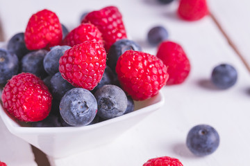 Raspberries  and blueberries on a bowl on a table