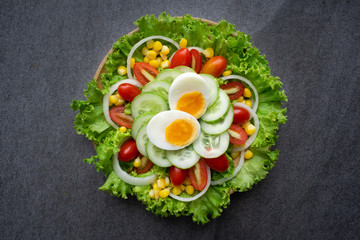 Healthy vegetables salad with boiled egg in wooden dish on table for vegetarian.