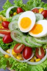 Healthy vegetables salad with boiled egg in wooden dish on table for vegetarian.