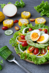 Healthy vegetables salad with boiled egg in wooden dish on table for vegetarian.