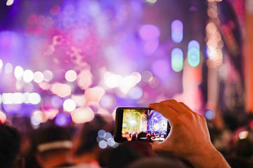 Close up of recording video with smartphone during a concert. colorful crowd on concert, disco...