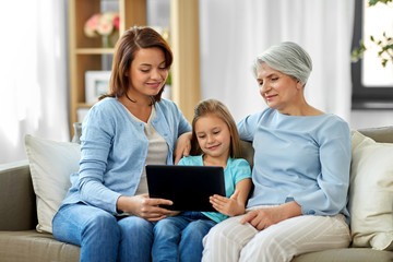 Fototapeta premium family, generation and technology concept - happy mother, daughter and grandmother with tablet computer at home