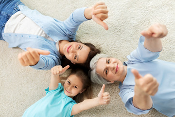 family, generation and female concept - mother, daughter and grandmother lying on floor and showing...