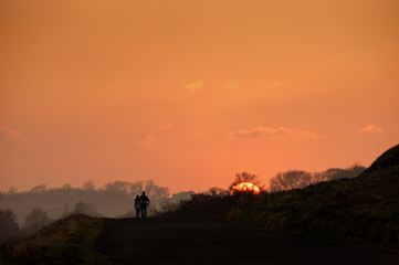 Obraz na płótnie Canvas A man and woman couple walking at sunset.