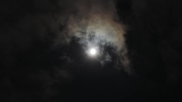 Amazing moonlight time-lapse in summer night. View of beautiful moon shining bright behind the clouds.