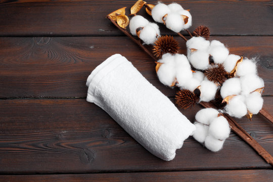 Cotton flowers with towel on wooden table