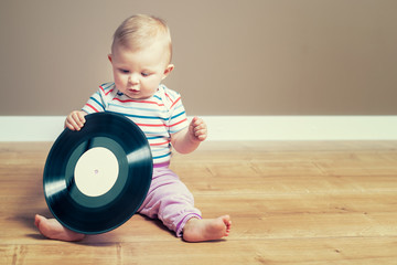 Little baby girl playing with a vinyl record with empty mockup label