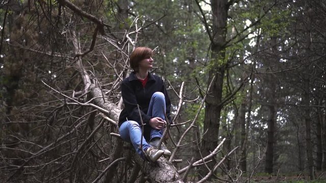 girl sitting on a tree in a wild forest