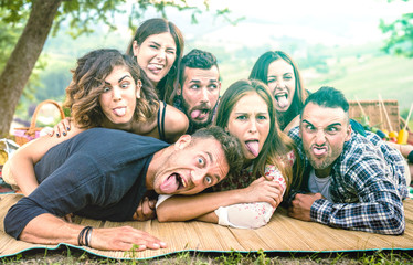 Millenial friends taking selfie with funny faces at pic nic barbecue - Happy youth friendship concept with millennial young people having fun together with tongue out -  Bright green azure filter