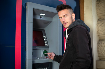 young man insert credit card to atm at night