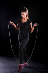 young woman standing with jumping rope isolated on a black background
