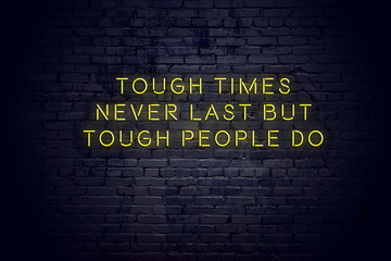 Neon sign with positive wise motivational quote against brick wall 