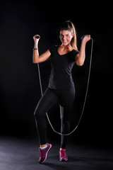 young woman standing with jumping rope isolated on a black background