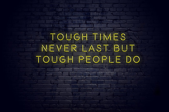 Neon sign with positive wise motivational quote against brick wall 