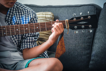 Close up image of a young hand plays acoustic guitar. Close-up view of a trendy child playing a...