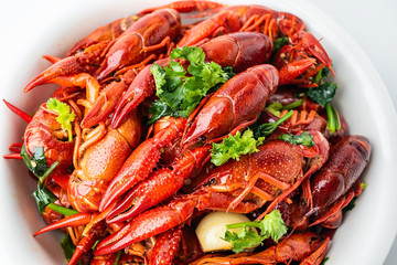 A large bowl of bright red delicious braised crayfish on a white background