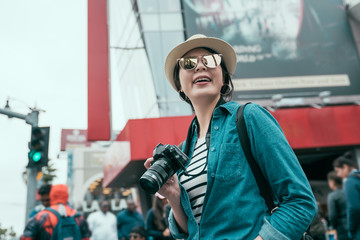 street young smiling happy asian woman tourist photographer posing with camera wearing straw hat...