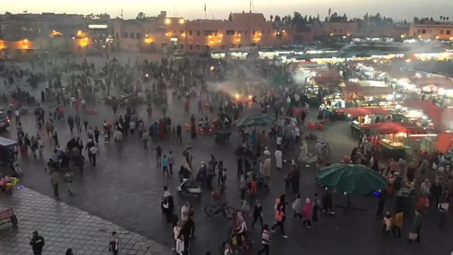  Marrakech, Morocco - March 2018: time lapse Jamaa El Fna square Marrakech, shot from above during sunset with people walking and smoking from the barbeque