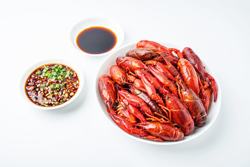 Delicious boiled crayfish and sauce on a saucer on a white background