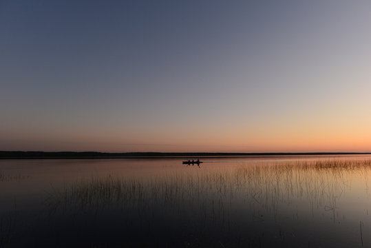 Tourists kayakers at sunset are returning from a hike on the quiet water of the lake
