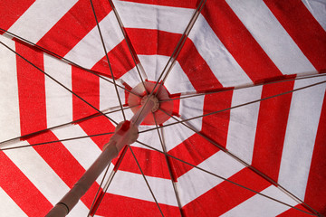 Part of red and white sun umbrella for sunbathing and protection of sun rays, closeup. Texture, material, pattern, background, wallpaper of colorful parasol beach umbrella. Holidays on tropical beach.