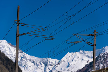 Eisenbahn Oberleitung, blauer HImmel, schneebedeckte Berge