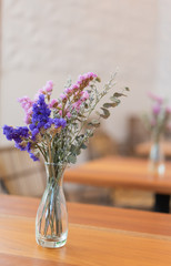 Beautiful dried flowers in glass vase on wood table,restaurant interior