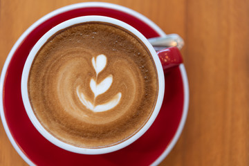 Hot coffee cup with latte art  in red cup on wood background,flat lay