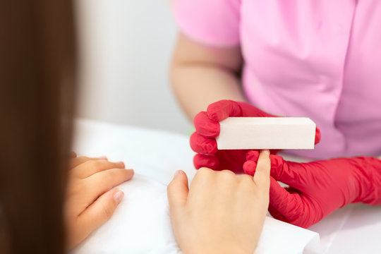 Woman in nail salon receiving manicure by beautician