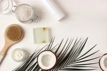 Obraz na płótnie Canvas Coconut, tropical leaf and care products on a colored background top view. Cosmetics with coconut extract for hair, body, face. Skin care, skin hydration. flatlay