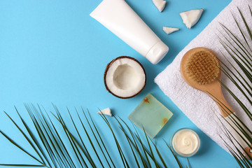 Fototapeta na wymiar Coconut, tropical leaf and care products on a colored background top view. Cosmetics with coconut extract for hair, body, face. Skin care, skin hydration. flatlay