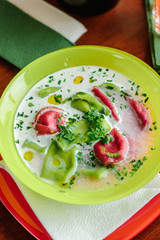 Green and red ravioli in soup for kids.