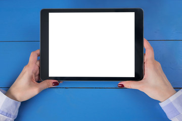 Woman sitting and looking at digital tablet computer device with white blank screen on blue wooden table - top view. Mock up, entertainment, copyspace, template, leisure time and technology concept 