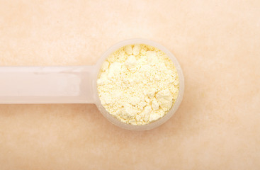 Süßlupinenmehl in Dosierlöffel auf braunem Hintergrund